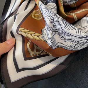 Close-up of vintage silk scarf featuring floral print and equestrian chain patterns
