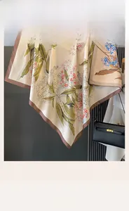 Dettaglio di un foulard in seta double-face con motivi floreali eleganti e bordi marroni rifiniti