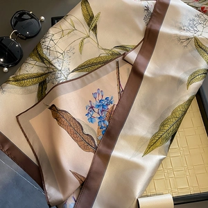Elegante foulard quadrato in seta con foglie d'olivo e bordo marrone su vassoio