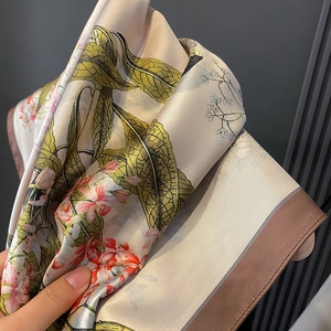 Elegante sciarpa in seta con stampa floreale, base beige e motivi di foglie verdi