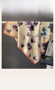 Detail showing elegant champagne silk scarf with purple rose pattern hanging on metal rack