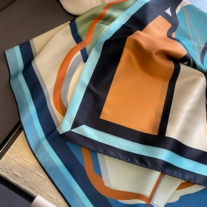 Detailed macro view of geometric silk scarf showing soft satin luster and fine edges