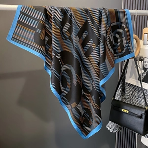 Detail eines Satin-Halstuchs mit Karo-Muster, Buchstaben-Prints und blauem Rand