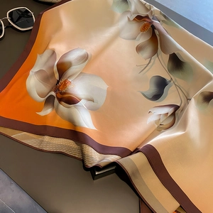 Détail d'une écharpe en soie satinée avec dégradé orange et imprimé floral blanc