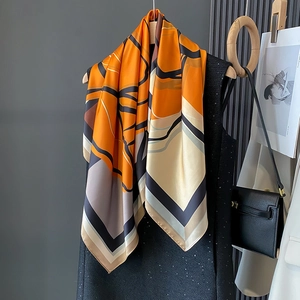 Elegant vibrant orange silk scarf with geometric floral patterns draped over grey dress