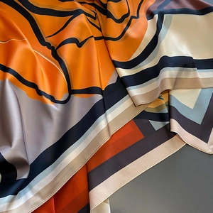 Close-up of luxury silk shawl with vibrant orange abstract patterns and smooth texture