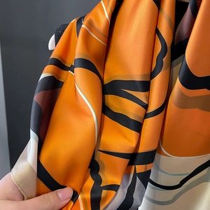 Detailed view of luxury satin shawl with modern abstract orange and black patterns