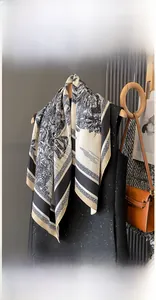 Detail shot of a 90x90cm faux silk scarf with tropical palm tree patterns on a rack