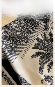 Detailed macro view of neat machine-rolled hem on a yellow floral silk scarf with palm patterns