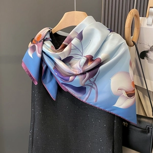 Écharpe élégante en soie bleu clair avec motif floral suspendue sur un cintre