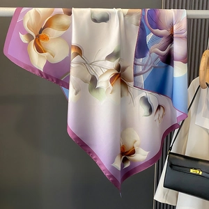 Détail d'un élégant foulard en soie aux motifs floraux violets sur un cintre