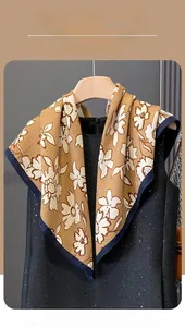 Detail of floral ginger silk scarf with navy border hanging on wooden hanger