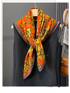Close-up of a floral print silk scarf in orange and yellow tied on a sequined vest