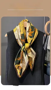 Close-up of floral print silk scarf in ginger and green hanging on a black vest