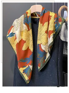Detail of vintage floral pattern silk scarf in vibrant orange and yellow hanging on a rack