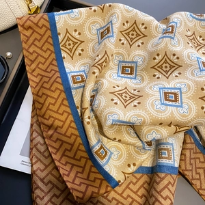 Detailed view of silk-textured vintage scarf with geometric patterns and pearl accessories