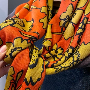 Detail of vibrant orange and yellow herringbone scarf with large floral print patterns