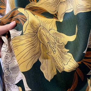 Detail of dark green herringbone fabric scarf with elegant yellow floral print