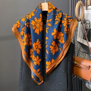 Detail of floral silk scarf with orange flower pattern and contrast satin hem border