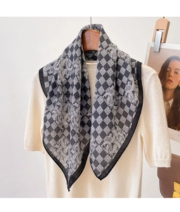 Detailed view of black and white checkerboard floral scarf styled on a beige knit top