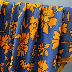 Detail of blue herringbone weave shawl with orange floral print and brown stitched edges