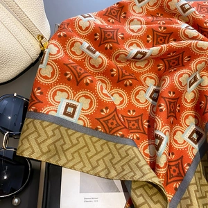 Detailed view of luxury vintage silk scarf with orange geometric patterns and gold borders