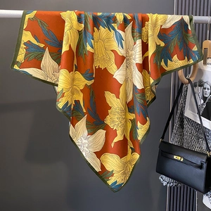 Detail of artistic floral silk square scarf with vibrant daffodil prints and rolled edges