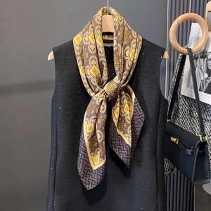 Detail view of vintage geometric silk scarf styled on a hanger with a black vest