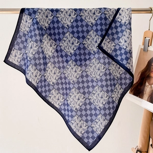 Detail of blue plaid square scarf with white rope patterns draped on a metal bar