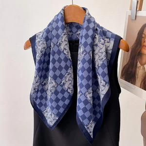 Close-up of blue checkerboard silk scarf with white feather patterns on a wooden hanger