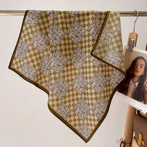 Detail of silk-feel scarf with brown checkerboard pattern and feather print finish