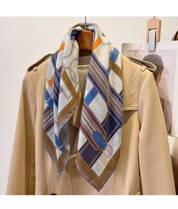 Detail of a geometric silk scarf tied on a beige trench coat for a stylish office look