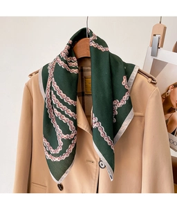 Detail of dark green silk scarf with chain pattern draped on a trench coat collar