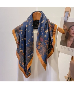 Detail of navy blue silk scarf with gold floral patterns and orange hem on a hanger