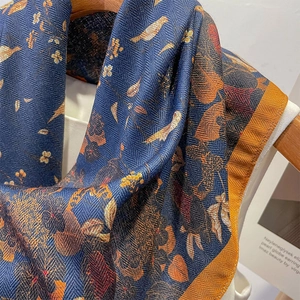 Elegant navy blue silk scarf with gold floral bird pattern on wooden hanger