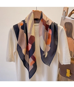 Detail of silk scarf with geometric navy and burgundy patterns on white knit top