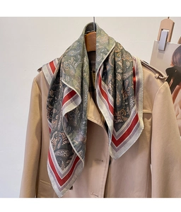 Macro detail of vintage paisley scarf with red stripe border on a khaki trench coat