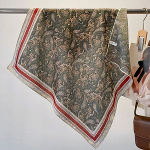 Vintage olive green paisley scarf with red stripe borders in a fashion display