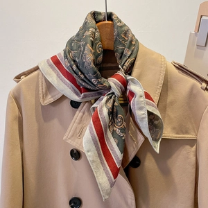 Retro paisley silk scarf in deep green styled on a khaki trench coat hanger