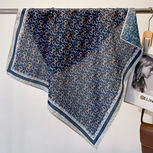 Detail of navy and orange silk scarf featuring classic horsebit chain pattern print