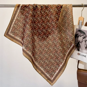 Detailed view of brown geometric horsebit pattern on silky neckerchief with contrast border