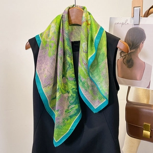 Abstract oil painting style silk scarf with green and blue prints on a wooden hanger