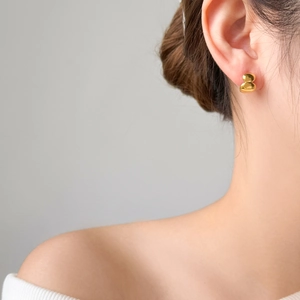 Close-up of polished 18K gold-plated stainless steel curved arc earrings on model