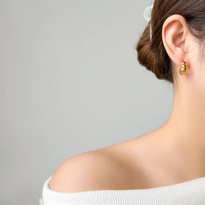 Close-up of golden multi-layer croissant hoop earrings worn on a model's ear