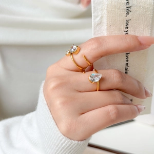 Dettaglio di anelli placcati oro 18K con zirconi a goccia e tondi indossati dal modello