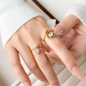 Dettaglio di anelli placcati oro 18K con zirconi rotondi e a goccia su fascia divisa