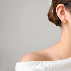 Close-up of triple-layered gold twist hoop earrings worn by a model for a stylish look