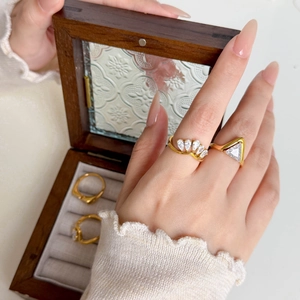 Detail view of 18K gold plated titanium rings with triangular and teardrop zircon stones