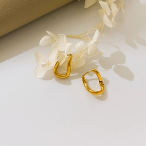 Artistic display of gold geometric U-shaped hollow earrings on minimalist white background
