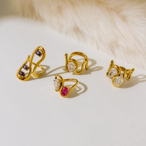 Détail de quatre bagues en titane plaqué or 18K avec lignes courbes et zircons violets